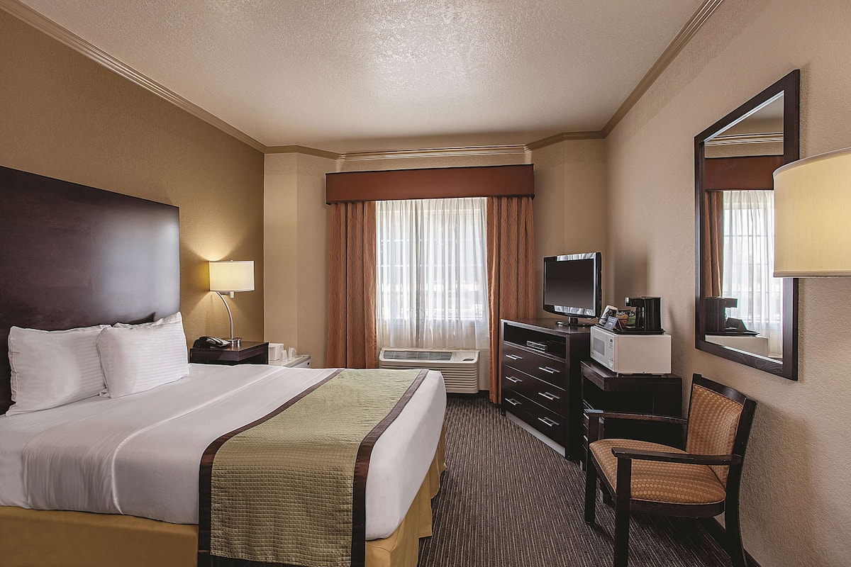 A hotel room with a large bed, a desk with a computer, a TV, and a chair.