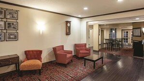 A lobby with two red armchairs, a wooden cabinet, a clock, and a dining area with a table and chairs. - La Quinta Inn & Suites by Wyndham Davis (Davis)