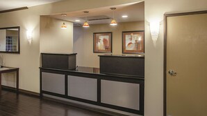 A reception area with a counter, framed artwork, and pendant lighting. - La Quinta Inn & Suites by Wyndham Davis (Davis)