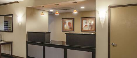 A reception area with a counter, framed artwork, and pendant lighting.
