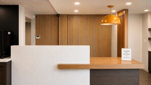 A hotel reception desk with a wooden panel backdrop, a 'Welcome to Our Hotel' sign, and a modern pendant light. - Best Western Plus Atlanta Sandy Springs Perimeter Hotel (Atlanta)