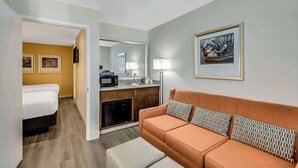 Une chambre d’hôtel compacte comprenant un lit, un canapé, une kitchenette et un coin repas.