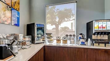 A coffee station with a coffee machine, a display case, and a window with a tree view.