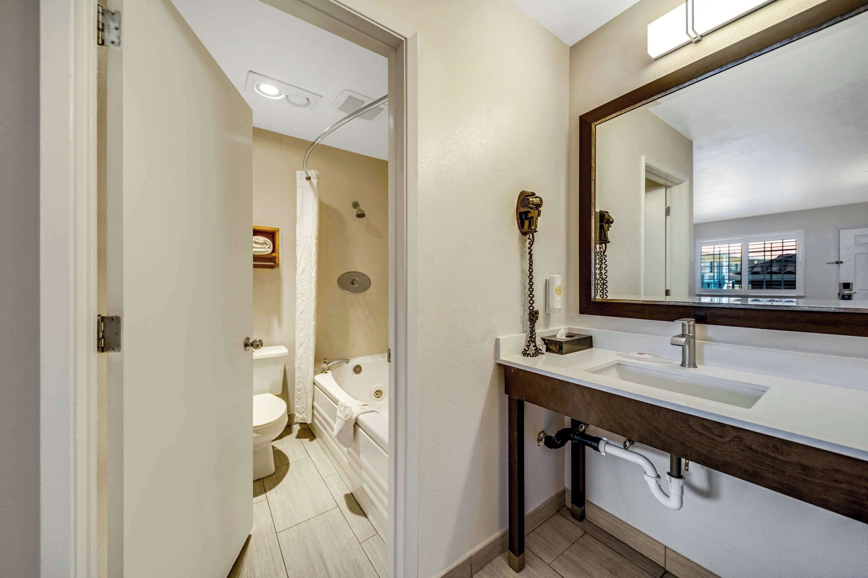 Une salle de bain moderne avec un lavabo blanc, un grand miroir et une baignoire.