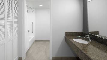 A modern bathroom with a granite countertop, a white sink, and a large mirror.