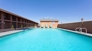 A swimming pool with a clear blue water, a building with a brown facade, and a clear sky. - Days Inn by Wyndham Chowchilla Gateway to Yosemite (Chowchilla)