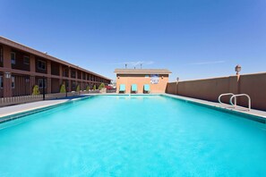 Una piscina al aire libre, sillones reclinables de piscina