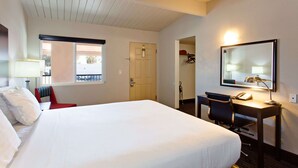 A hotel room with a large bed, a desk with a chair, a mirror, and a window. - Days Inn by Wyndham Chowchilla Gateway to Yosemite (Chowchilla)