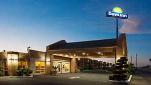 A Days Inn hotel with a well-lit entrance, a parking lot, and a clear sky. - Days Inn by Wyndham Chowchilla Gateway to Yosemite (Chowchilla)