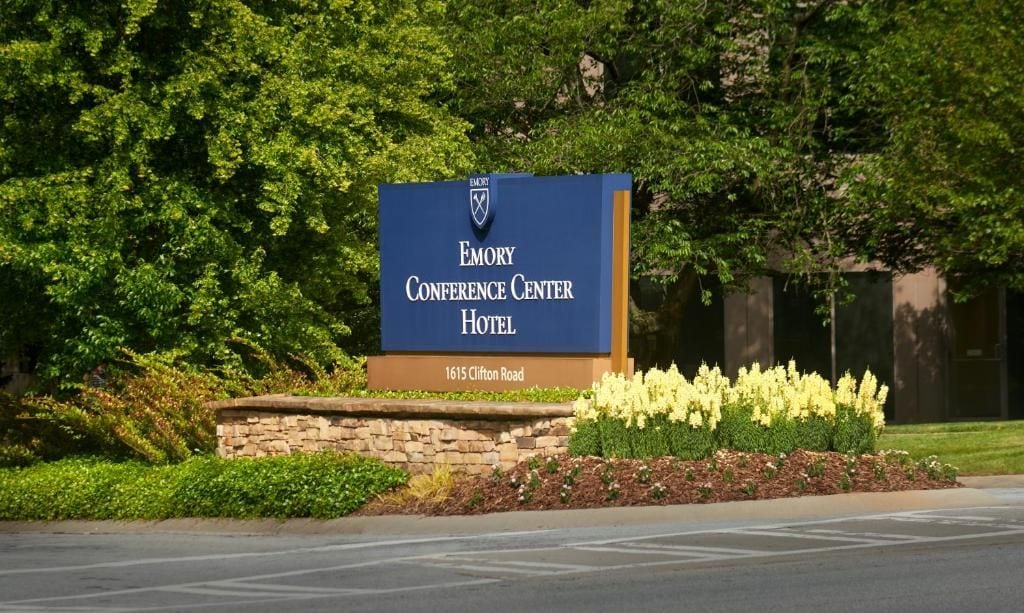 A sign for the Emory Conference Center Hotel with a stone wall and flower bed in front.