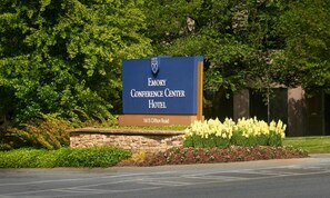 A sign for the Emory Conference Center Hotel with a stone wall and flower bed in front.