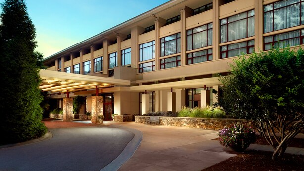 A multi-story hotel with a covered entrance, stone pillars, and a landscaped garden. - Emory Conference Center Hotel (Atlanta)