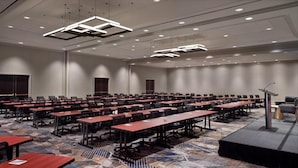 A conference room with multiple tables and chairs, a stage with a podium, and a carpeted floor. - Emory Conference Center Hotel (Atlanta)