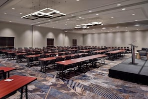 A conference room with multiple tables and chairs, a stage with a podium, and a carpeted floor. - Emory Conference Center Hotel (Atlanta)