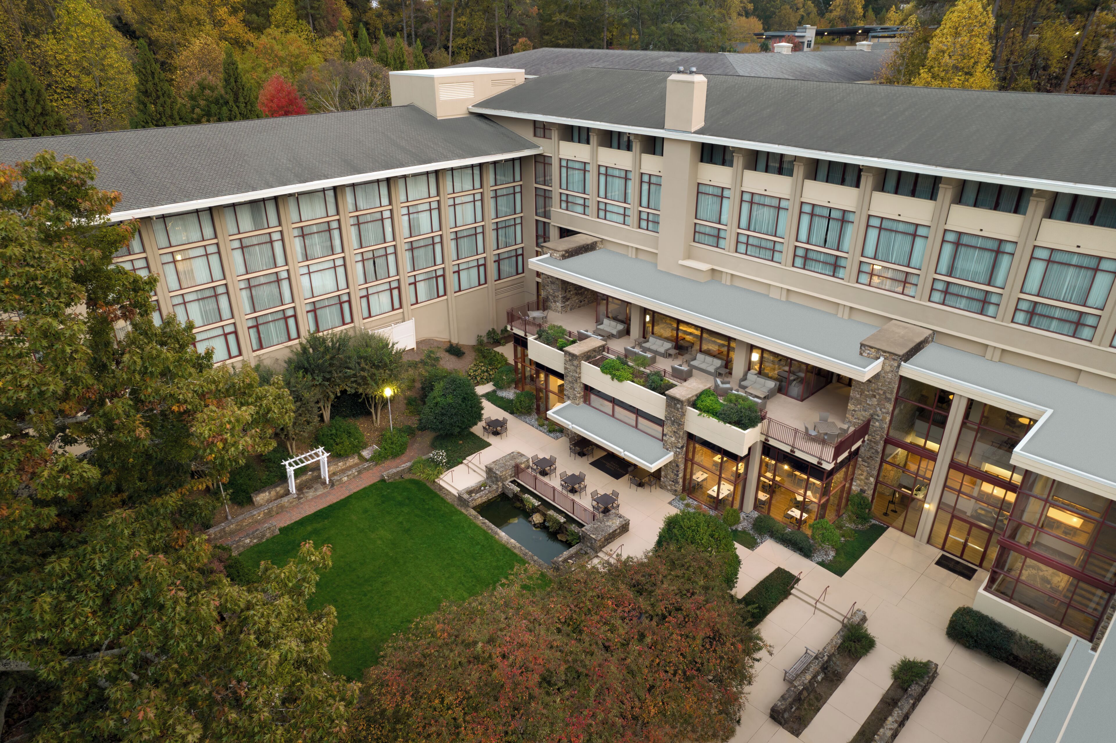 A multi-story building with a courtyard featuring outdoor seating and a small water feature.