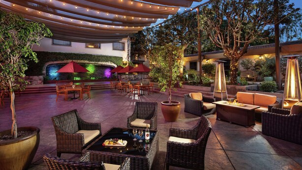 An outdoor patio area with wicker furniture, string lights, and a water feature. - DoubleTree by Hilton Claremont (Claremont)