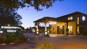 A hotel entrance with a covered outdoor area, a sign for 'DOUBLETREE', and a well-lit driveway. - DoubleTree by Hilton Claremont (Claremont)