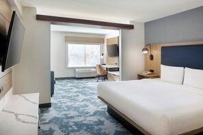 Hotellihuone, jossa on sänky, työpöytä, tuoli, televisio ja ikkuna.