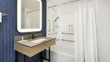 A bathroom with a wooden vanity, a large mirror, a bathtub, and a shower.