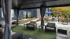 Un patio al aire libre con mobiliario de mimbre, una piscina y una zona de estar cubierta.