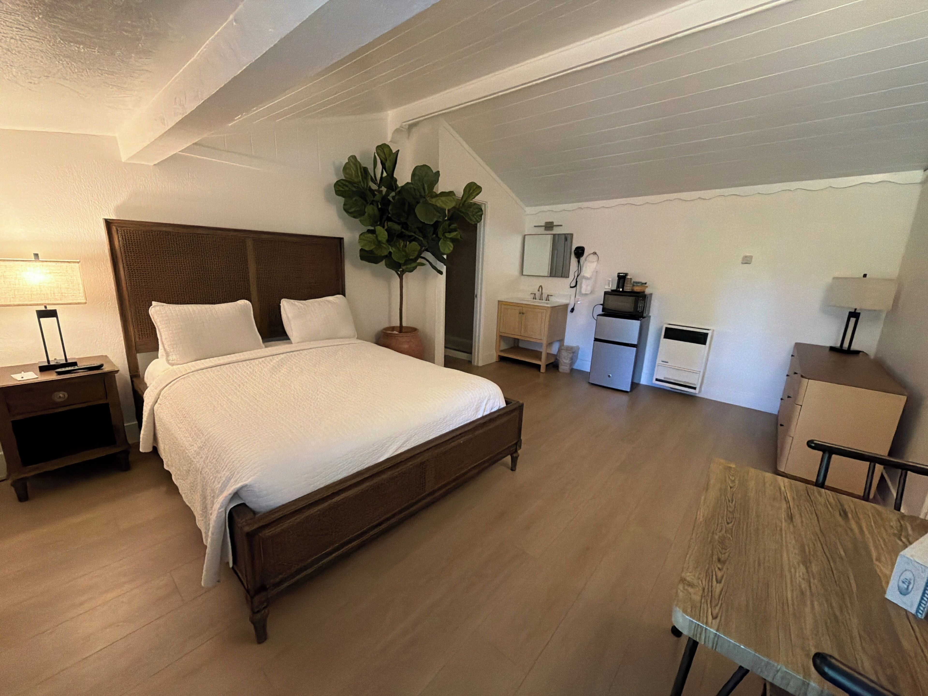 Ein Schlafzimmer mit Bett, Nachttisch, Lampe und einem Blumentopf.
