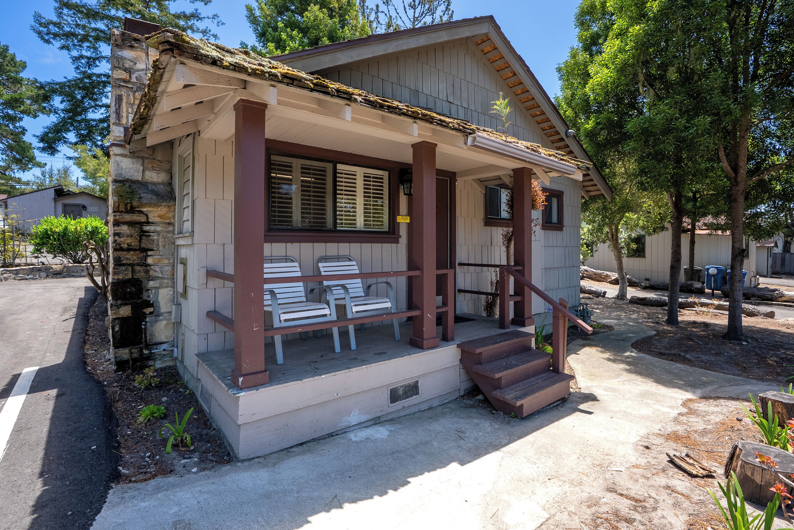 A small, single-story building with a porch and a few chairs.