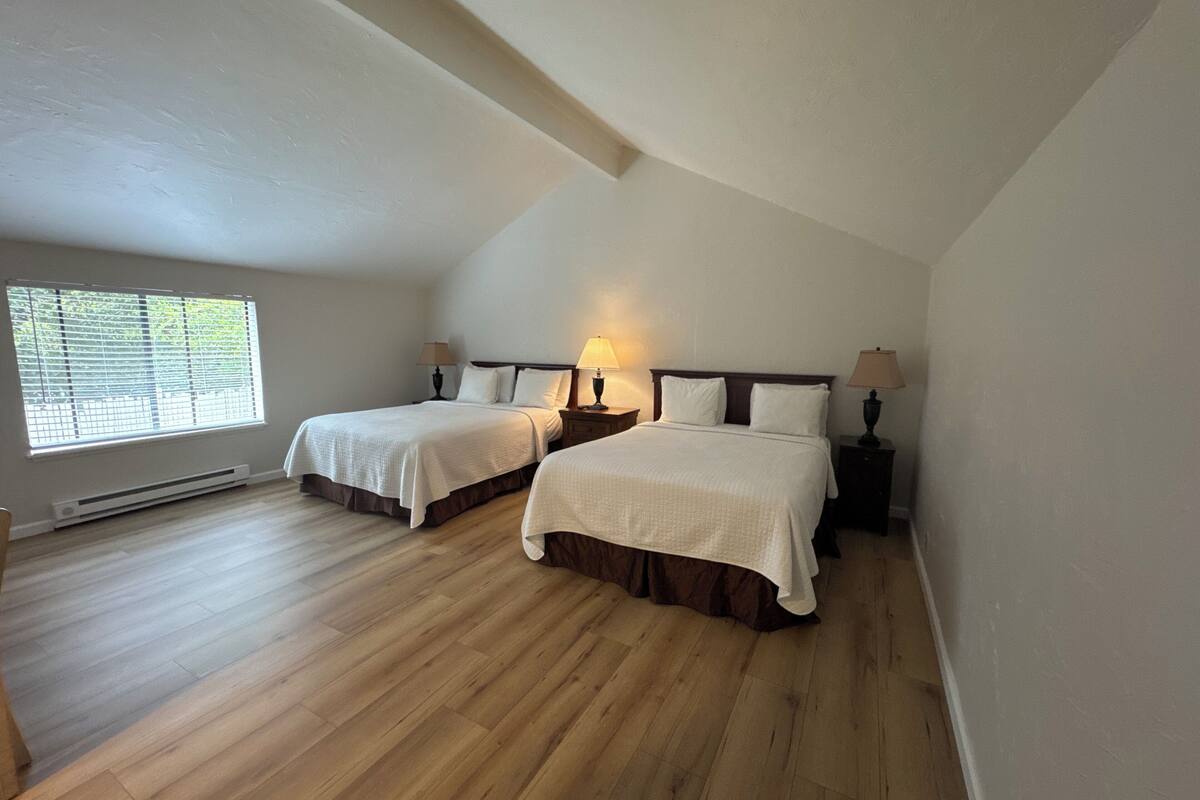 Un dormitorio con dos camas, una ventana con persianas y un radiador.