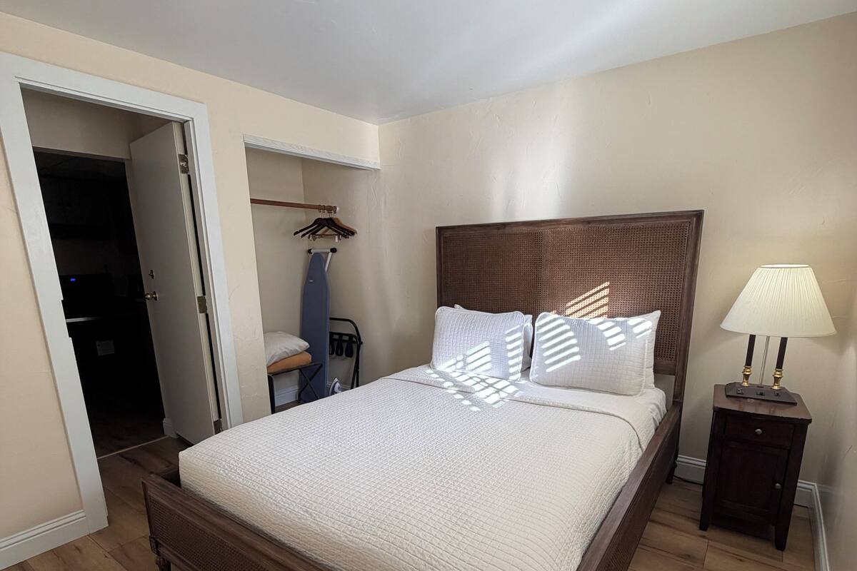 Un dormitorio con una cama de madera, una mesita de noche con lámpara y un armario.