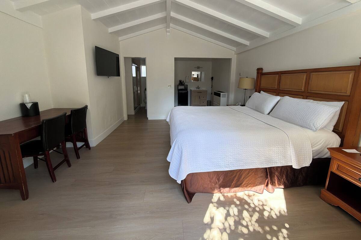 Un dormitorio con una cama grande, un escritorio y un televisor en la pared.