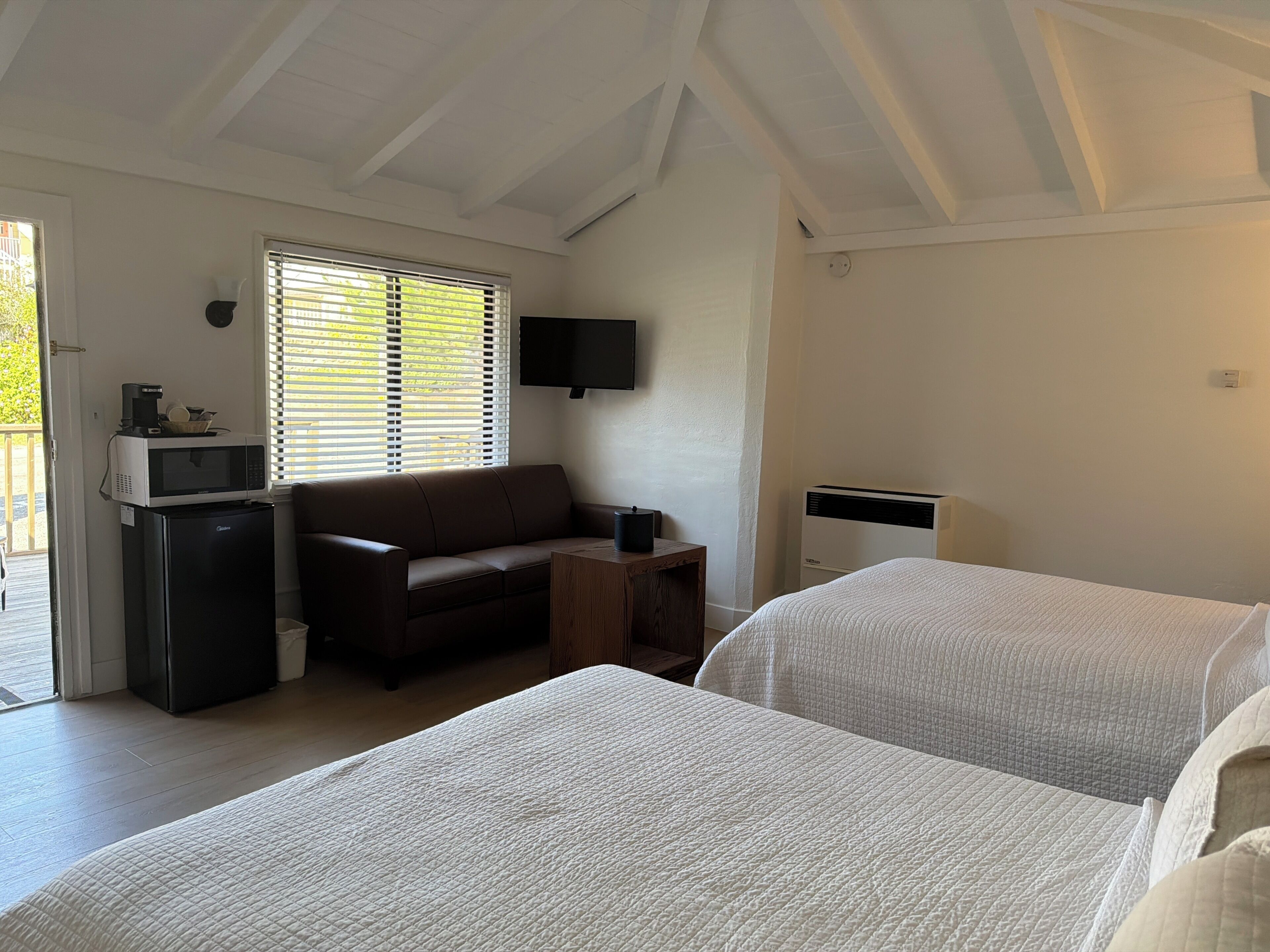 A room with a bed, a sofa, a TV, a microwave, and a refrigerator.