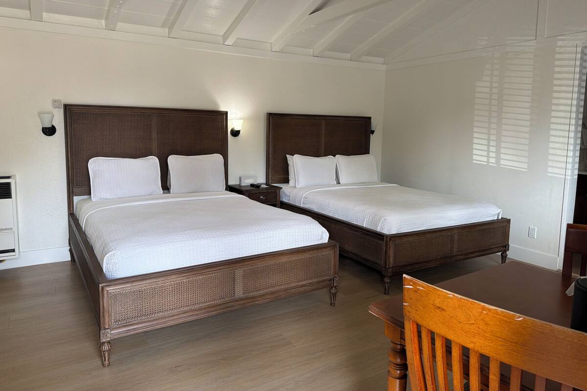 Una habitación de hotel con dos camas de madera, una mesa de madera y una silla.