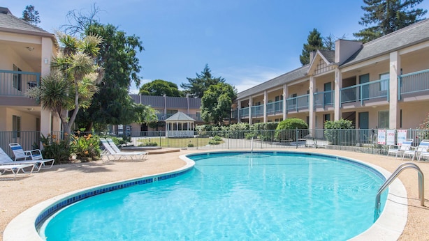 A swimming pool surrounded by lounge chairs and a building with balconies.
