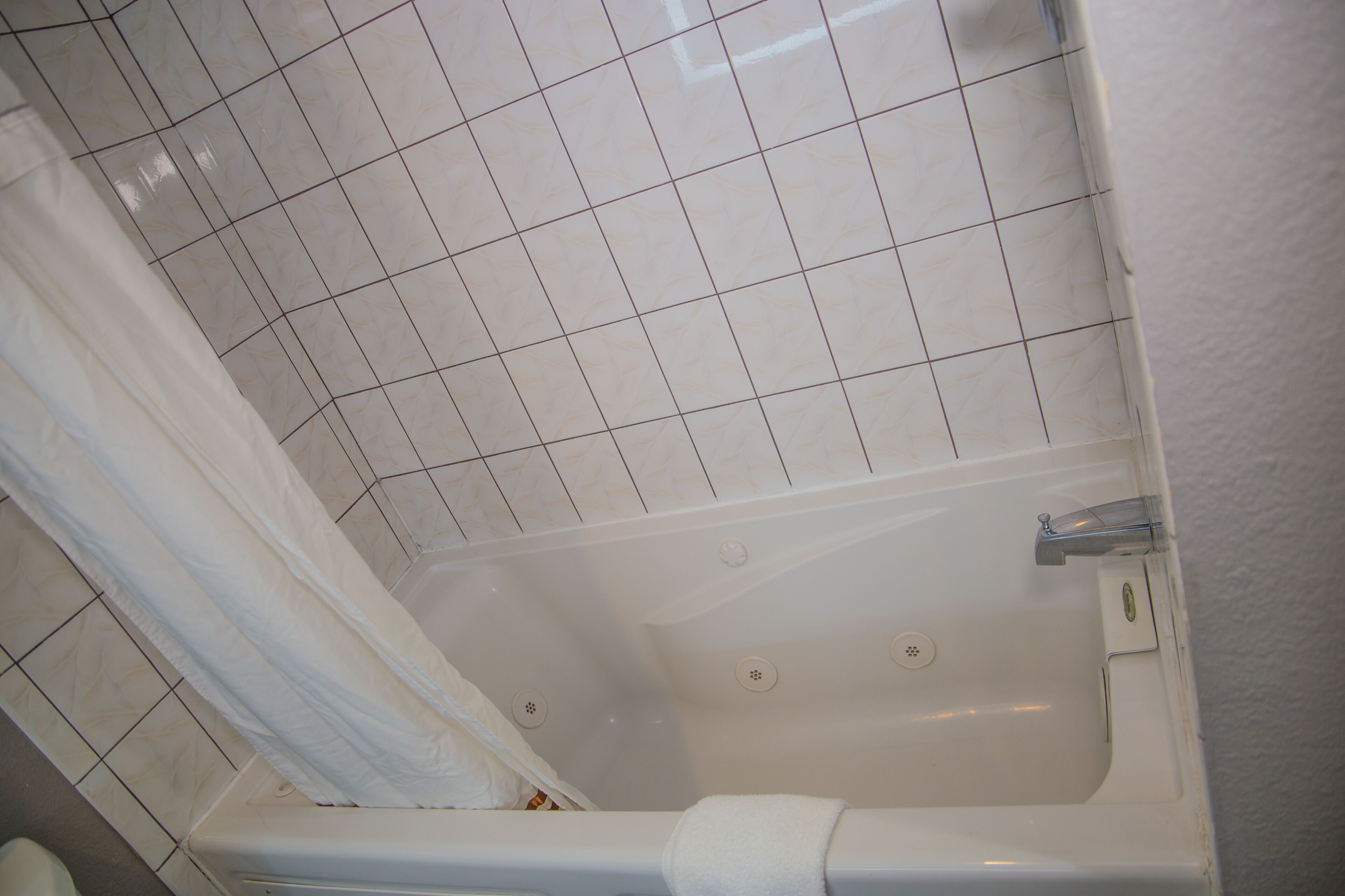 A bathroom with a bathtub, tiled walls, and a shower curtain.