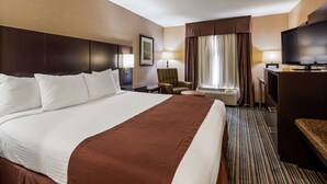 A hotel room with a large bed, a desk with a television, a chair, a lamp, and a window with curtains. - Best Western Brentwood Inn (Brentwood)