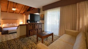 A hotel room with a bed, a sofa, a TV, and a small table. - Best Western The Inn & Suites Pacific Grove (Pacific Grove)