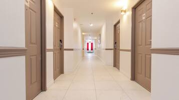 A hotel hallway with doors numbered 132 and 133, leading to a red curtain at the end.