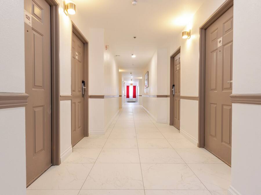 A hotel hallway with doors numbered 132 and 133, leading to a red curtain at the end.