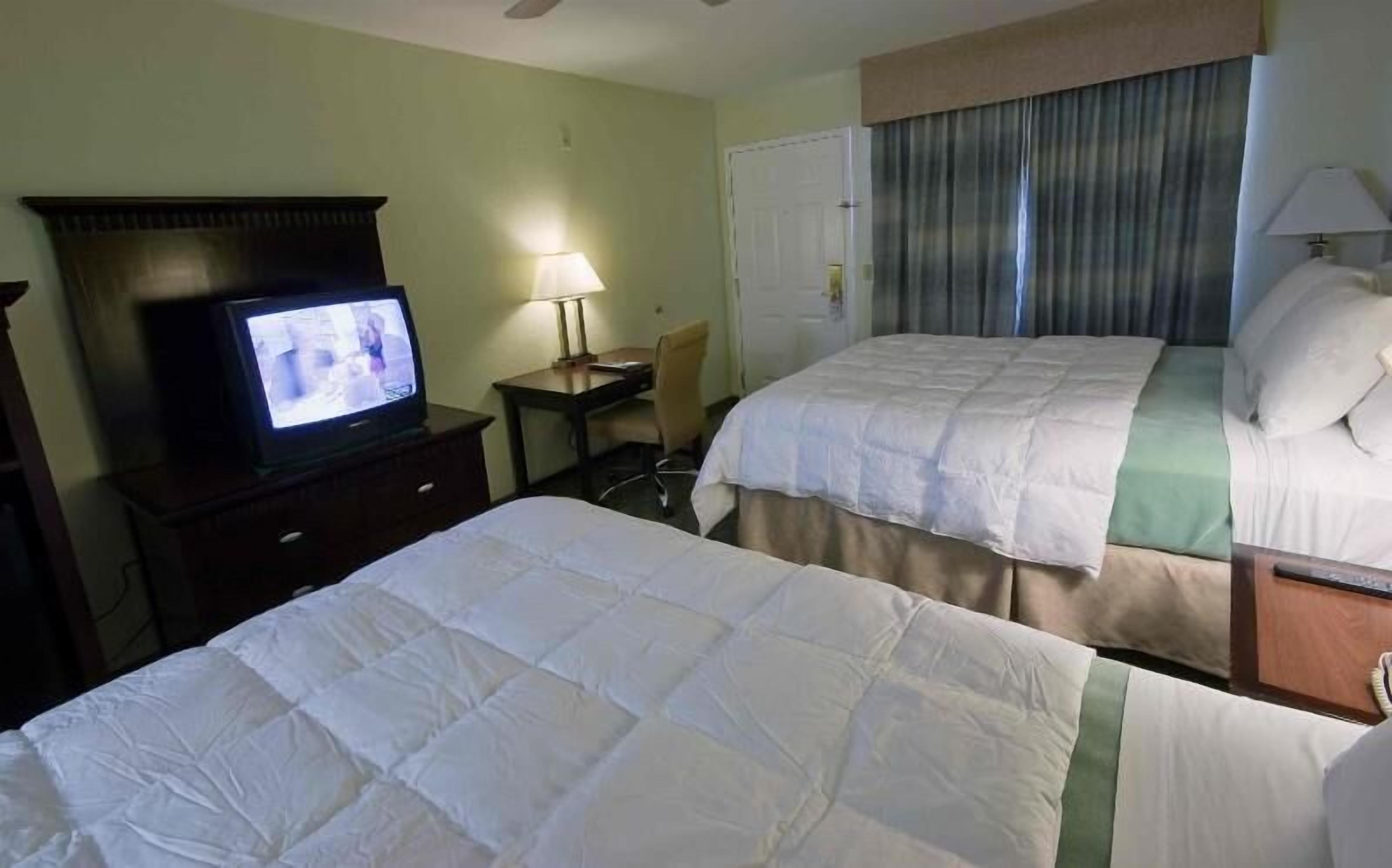 Een hotelkamer met twee bedden, een televisie, een bureau en een stoel.