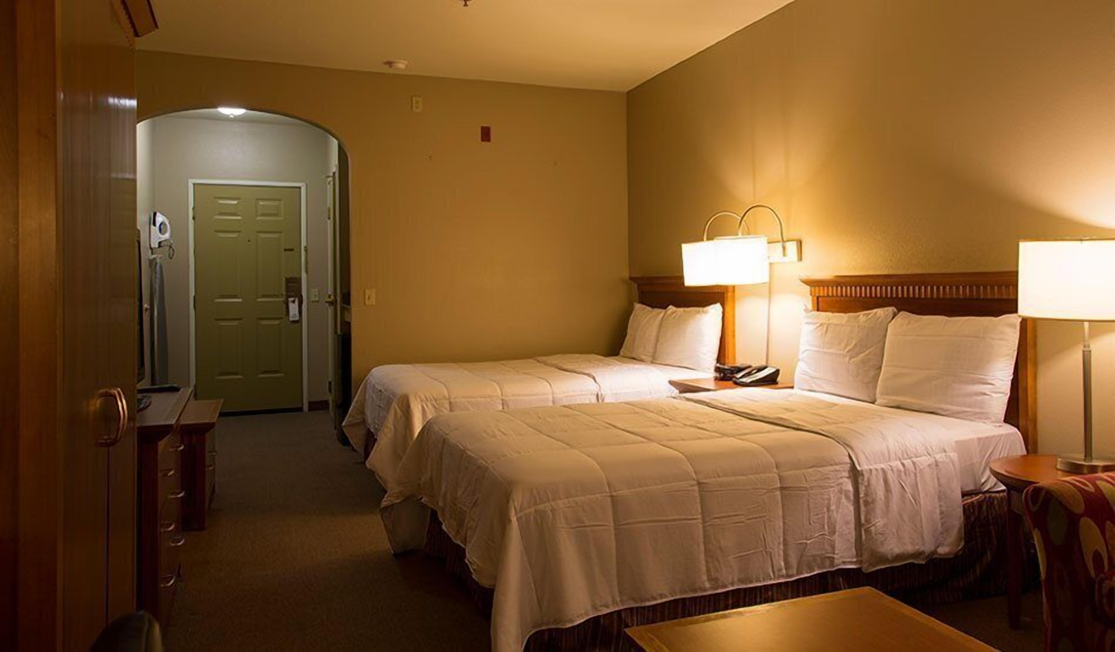 A hotel room with two beds, a desk, and a chair.
