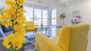 A modern hotel lobby with yellow chairs, a large window offering a view of the city, and a plant with yellow flowers.