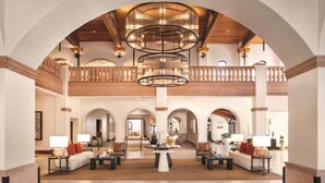 Un'ampia hall con soffitto alto, numerosi archi e un lampadario centrale. Sono presenti aree salotto con tavoli e lampade.