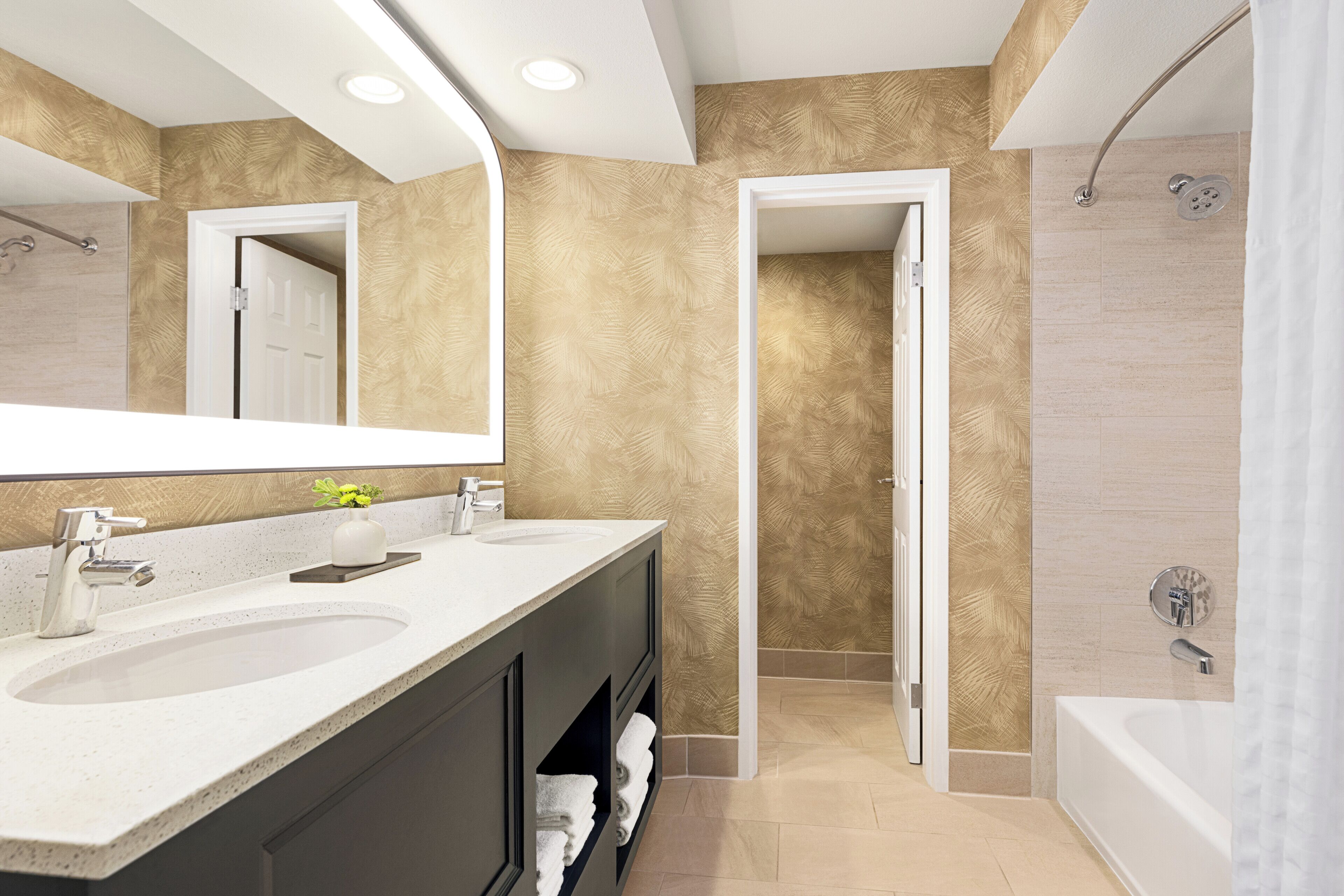 A modern bathroom with a double sink vanity, a large mirror, a shower area, and a bathtub.