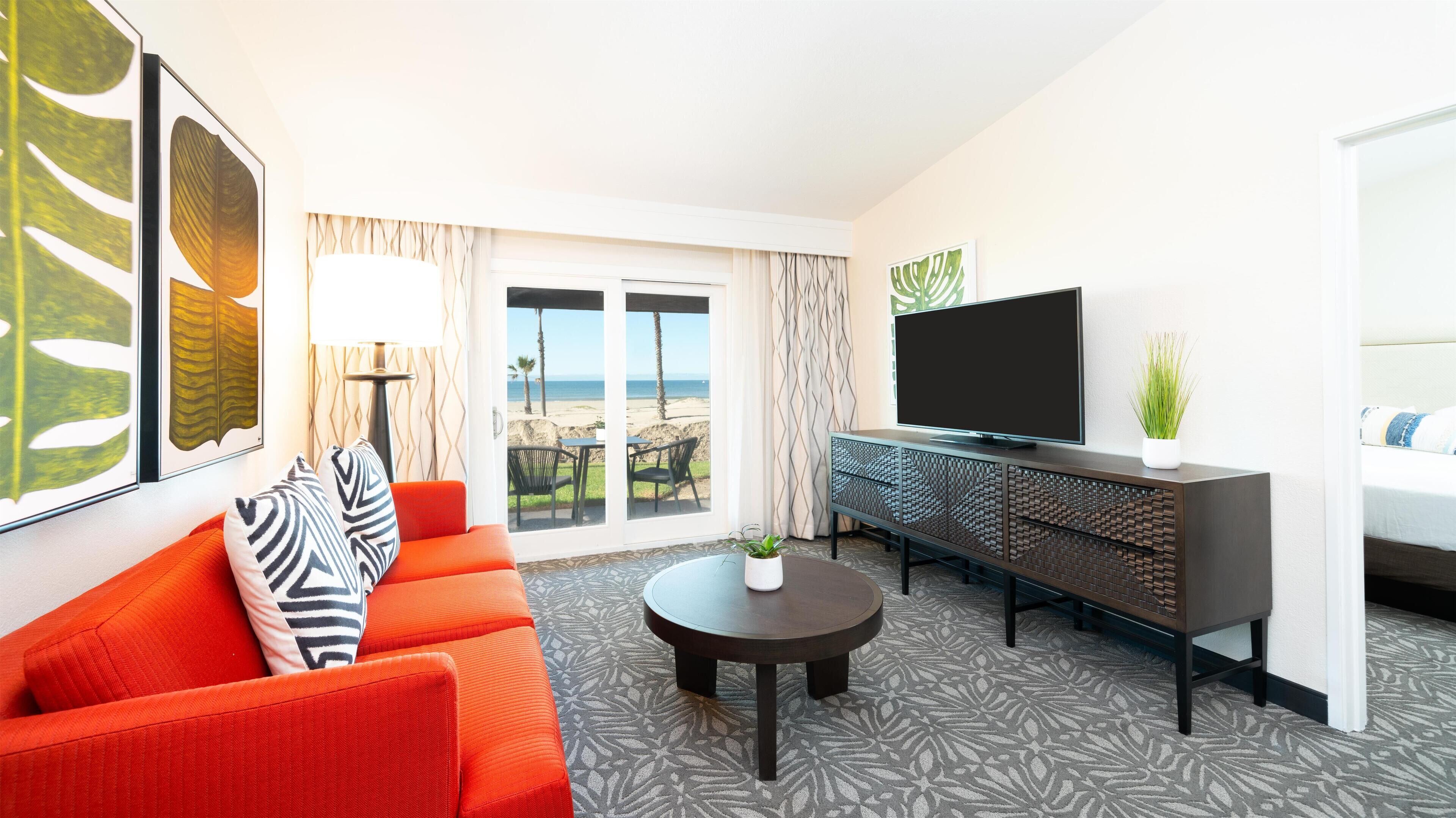 Une chambre d’hôtel avec un canapé, une télévision, une table basse et vue sur la plage.