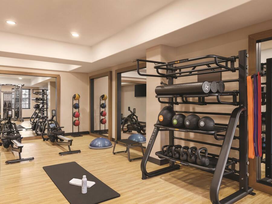 A gym with exercise equipment, a mirror, and a wooden floor.