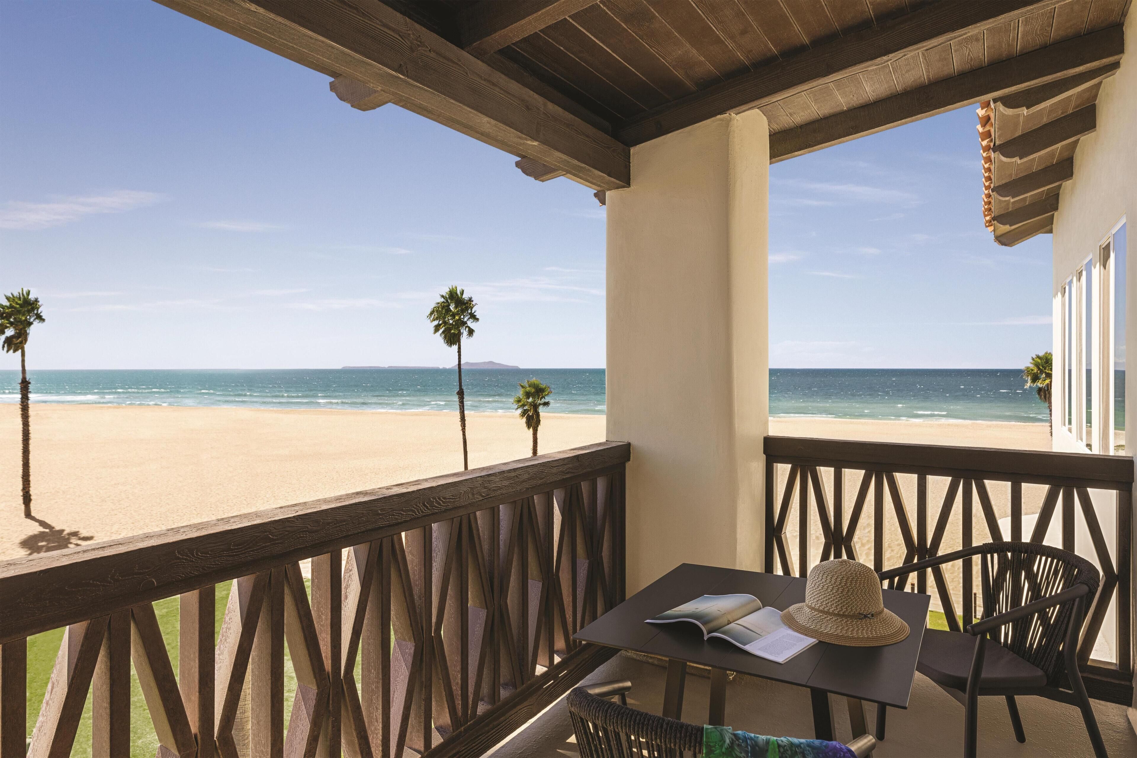 Un balcon donnant sur la plage, une table avec un chapeau et une chaise.