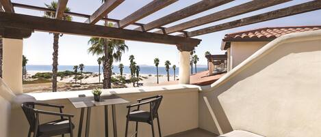 A balcony with a wooden pergola, two chairs, a table, and a sofa.