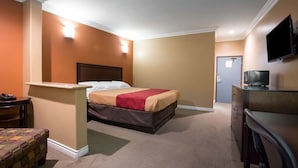 Ein Hotelzimmer mit Bett, Schreibtisch, Stuhl, Fernseher und einer Tür.