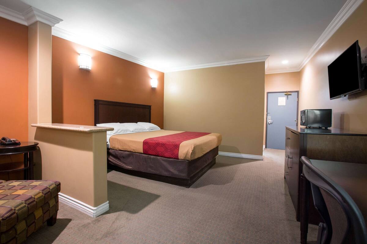 Ein Hotelzimmer mit Bett, Schreibtisch, Stuhl, Fernseher und einer Tür.