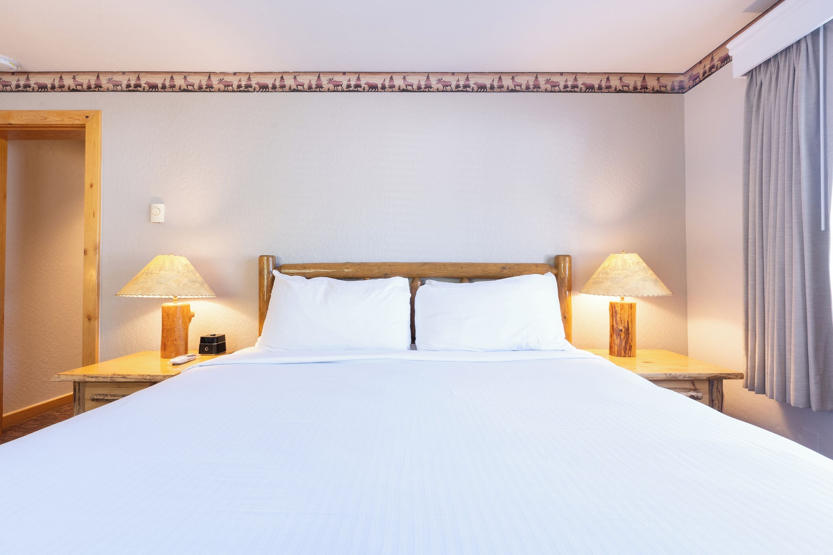 Ein Hotelzimmer mit einem großen Bett, zwei Nachttischlampen und einem hölzernen Kopfteil.