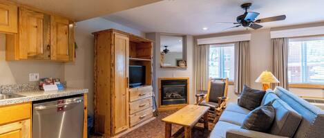 A compact living space with a kitchenette, a dining area, a sofa, and a fireplace.